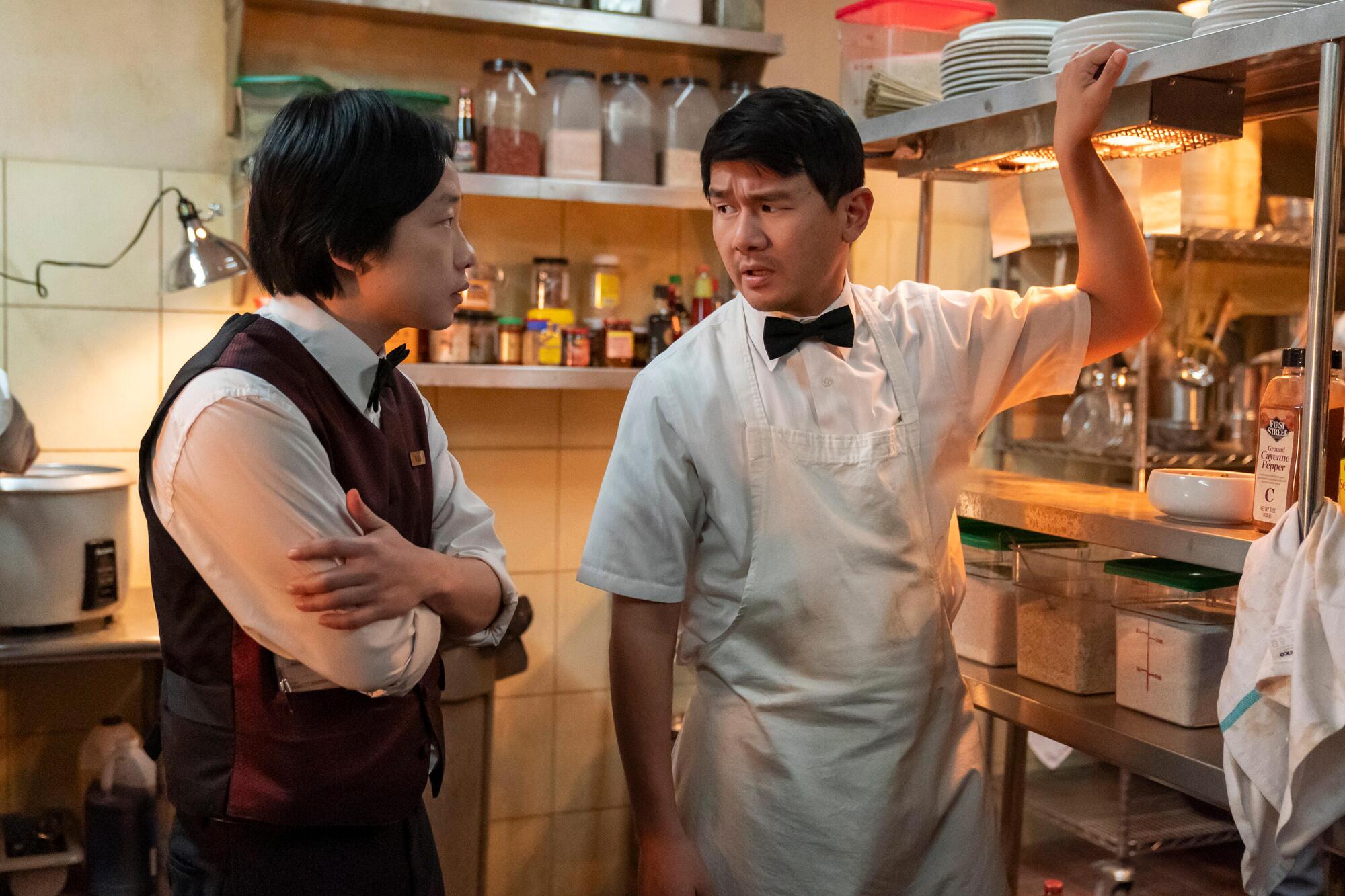 Two Asian restaurant workers in the kitchen.