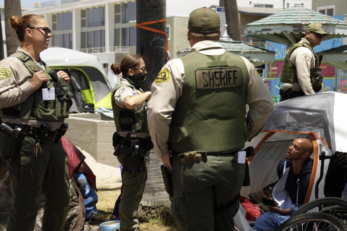 Sheriff's deputies approach a man living in a tent.