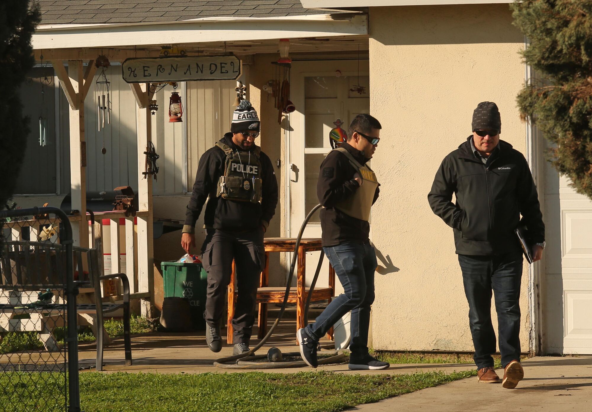 Three federal agents leaving through the driveway of a residential property