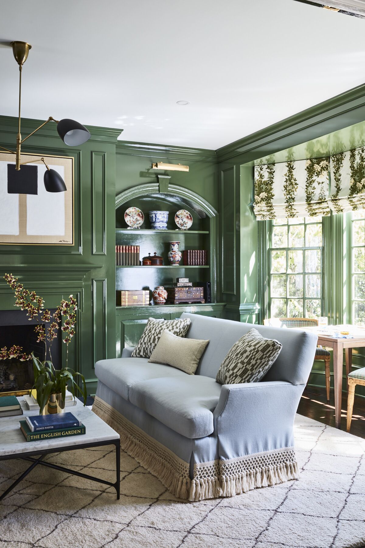 An airy home library has walls painted in a brighter shade of green with a glossy finish.