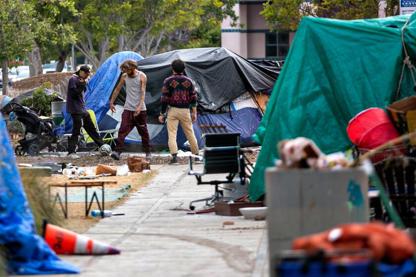 VENICE, CA - MAY 23: A group men kick around a soccer ball at a homeless encampment outside Abbot Kinney Memorial Branch Library on Monday, May 23, 2022 in Venice, CA. (Jason Armond / Los Angeles Times)