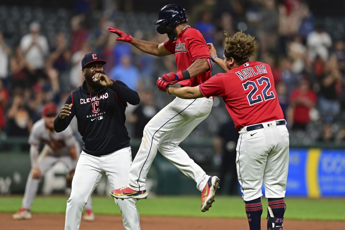 Cleveland Guardians' Amed Rosario, center, celebrates with Josh Naylor (22) and Franmil Reyes, left, after hitting an RBI-single during the 10th inning of a baseball game against the Arizona Diamondbacks, Monday, Aug. 1, 2022, in Cleveland. (AP Photo/David Dermer)