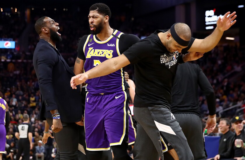 From left, LeBron James, Anthony Davis and Jared Dudley are pumped up in the Lakers' rout of the Warriors on Thursday night. With James sidelined, Davis had 23 points.