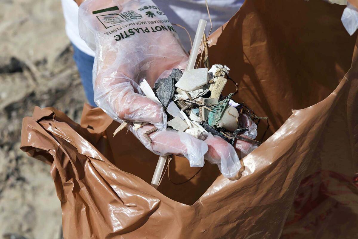 A volunteer holds a handful of plastic thrash found along the Huntington Beach State Beach.