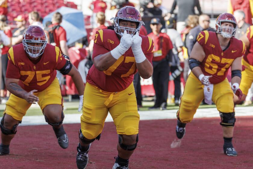 LOS ANGELES, CA - NOVEMBER 30, 2024: USC Trojans offensive lineman Alani Noa (77), middle, with USC Trojans offensive lineman Amos Talalele (75) and USC Trojans offensive lineman Kilian O'Connor (67) warm up before the game against Notre Dame at the LA Coliseum on November 30, 2024 in Los Angeles, California. (Gina Ferazzi / Los Angeles Times)