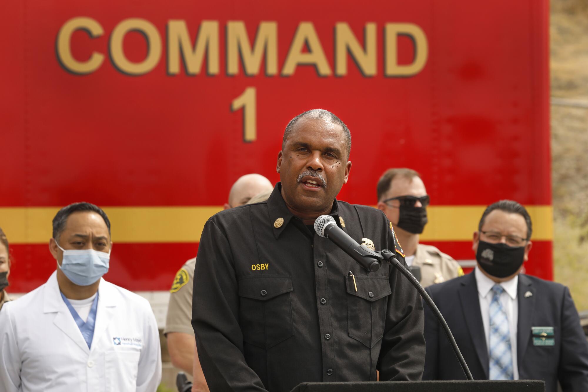 A man in uniform stands at a lectern behind a microphone.