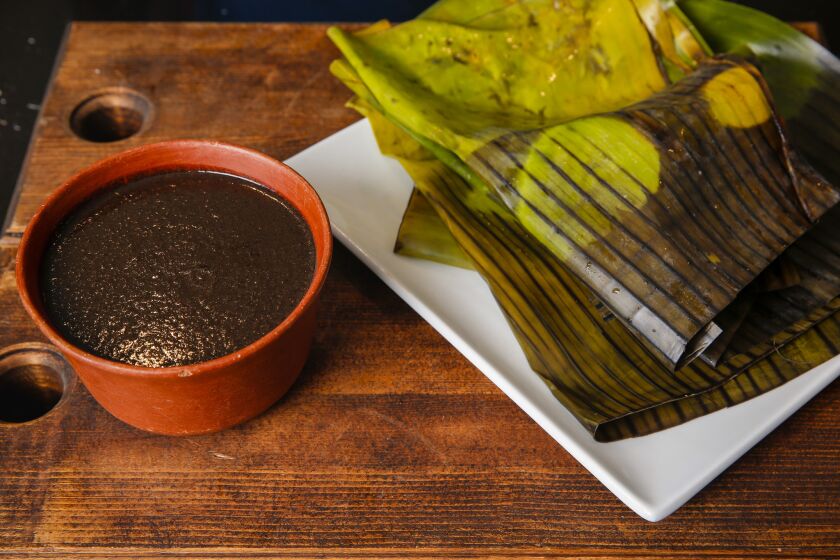 A bowl of mole and banana leaves, in preparation for mole tamales, part of a classic Oaxacan Christmas meal at the Los Angeles home of Bricia Lopez.