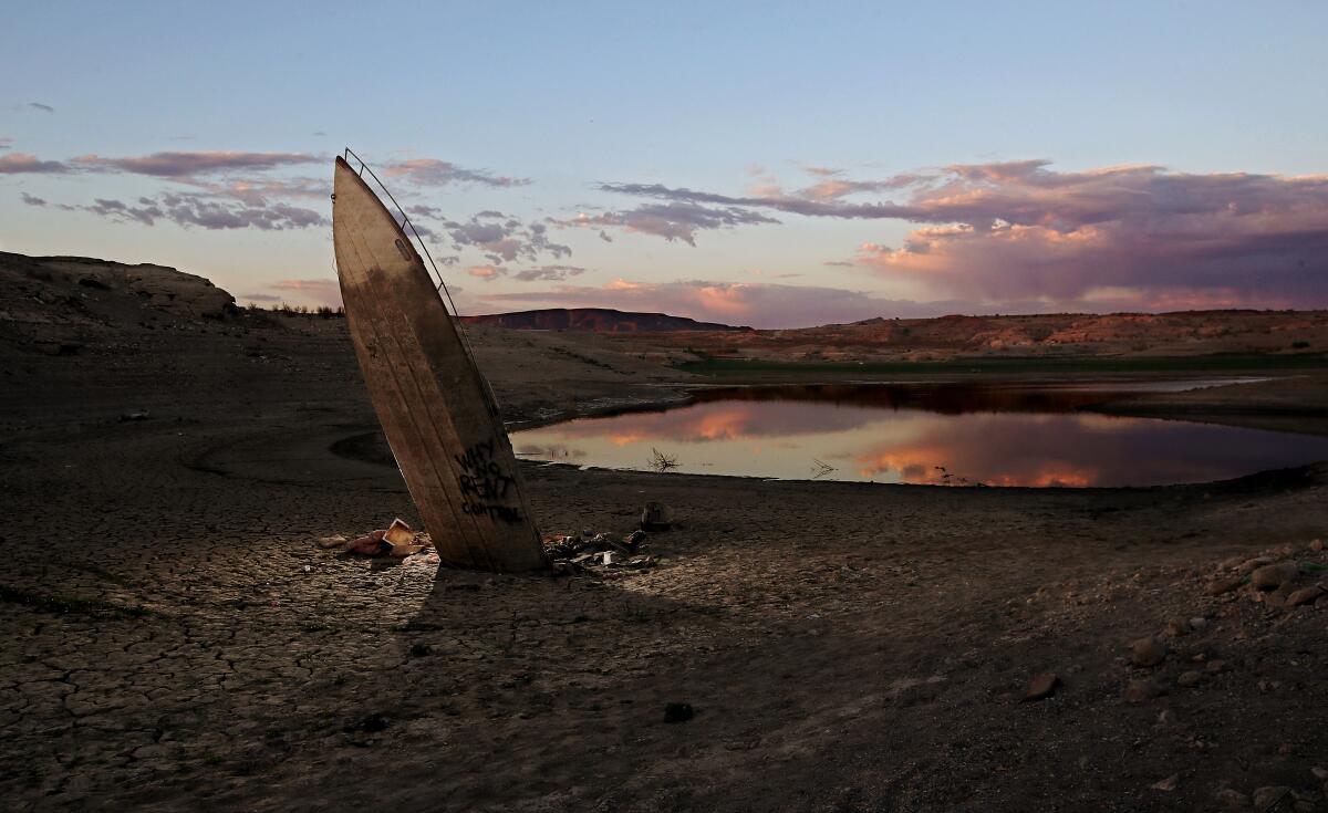A long-sunken boat juts up from a drying lakebed at sunset