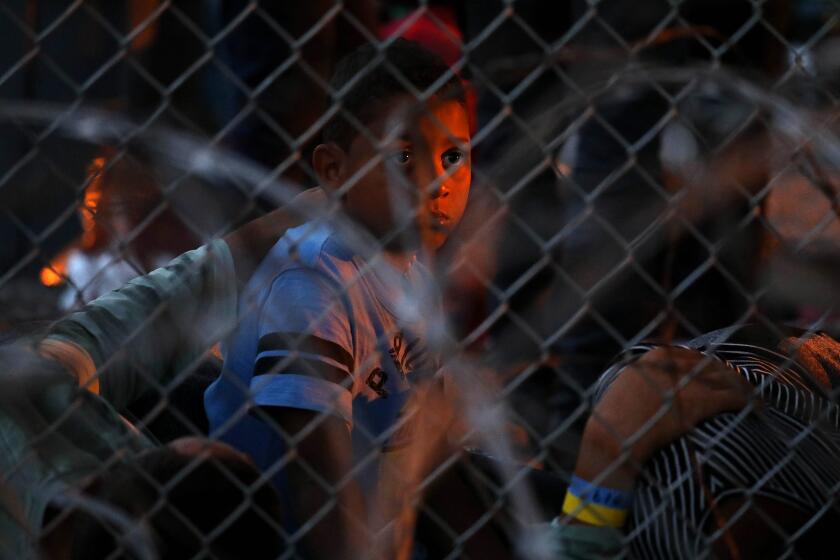 EL PASO, TEXAS -- THURSDAY, MARCH 28, 2019: Hundreds of migrants seeking asylum are held in a temporary transition area under the Paso Del Norte bridge in El Paso, Texas, on March 28, 2019. U.S. Border Patrol - Paso del Norte Port of Entry, set up the outdoor pen where some migrants, including young children and babies, have been held there for as many as four days and have been forced to sleep outside on bare gravel with only thin Mylar blankets to protect them from the cold desert nights. (Gary Coronado / Los Angeles Times)