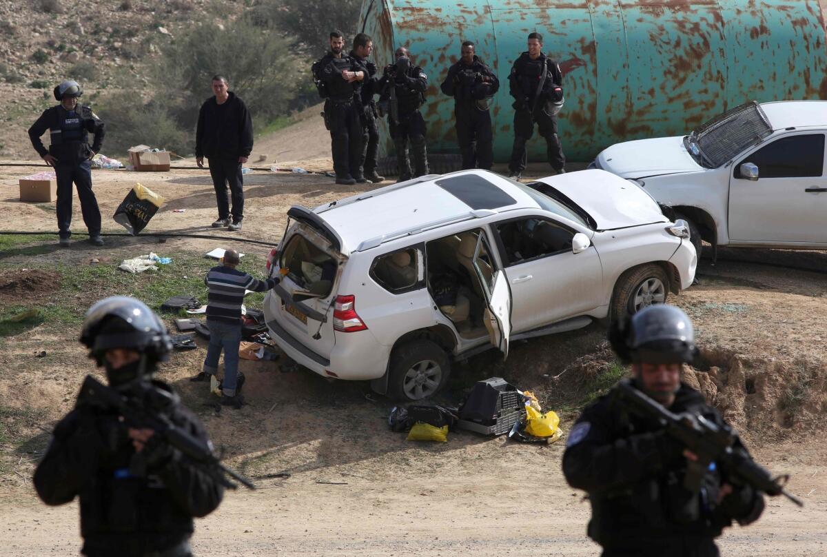 Israeli policemen stand guard next to a car, reportedly used in a ramming attack that left one police officer dead. Police shot and killed the driver.