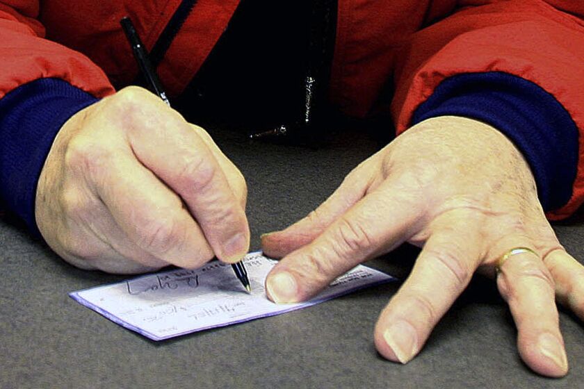 FILE - A man signs a check in Anchorage, Alaska, April 17, 2006,. Check fraud tied to mail theft is up nationwide, according to a recent alert. The U.S. Postal Service is vulnerable, and thieves who can access your checks can change the amount and ferret those funds right out of your bank account. (AP Photo/Al Grillo, File)