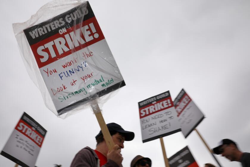 Studio City, CA - May 09: A supporter of the Writer's Guild of America strike walks with a sign that reads, "You want the funny? Look at your streaming residual model," as people picket along Colfax Avenue, at Radford Studios Center, in Studio City, CA, Tuesday, May 9, 2023. (Jay L. Clendenin / Los Angeles Times)