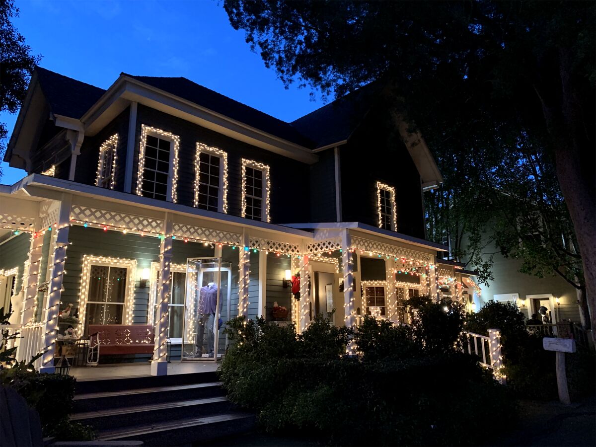 A house with Christmas lights around the windows and up the columns.