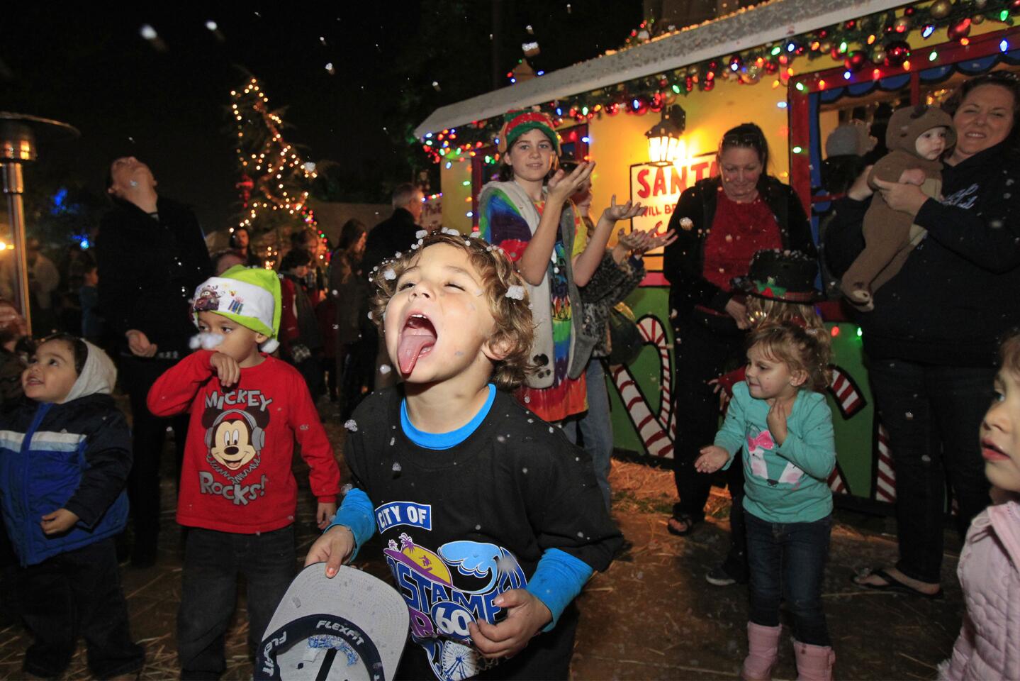 Nicky Johnson, 6, of Costa Mesa sticks his tongue out to catch snow during the opening for the Snoopy House at Costa Mesa City Hall on Friday.