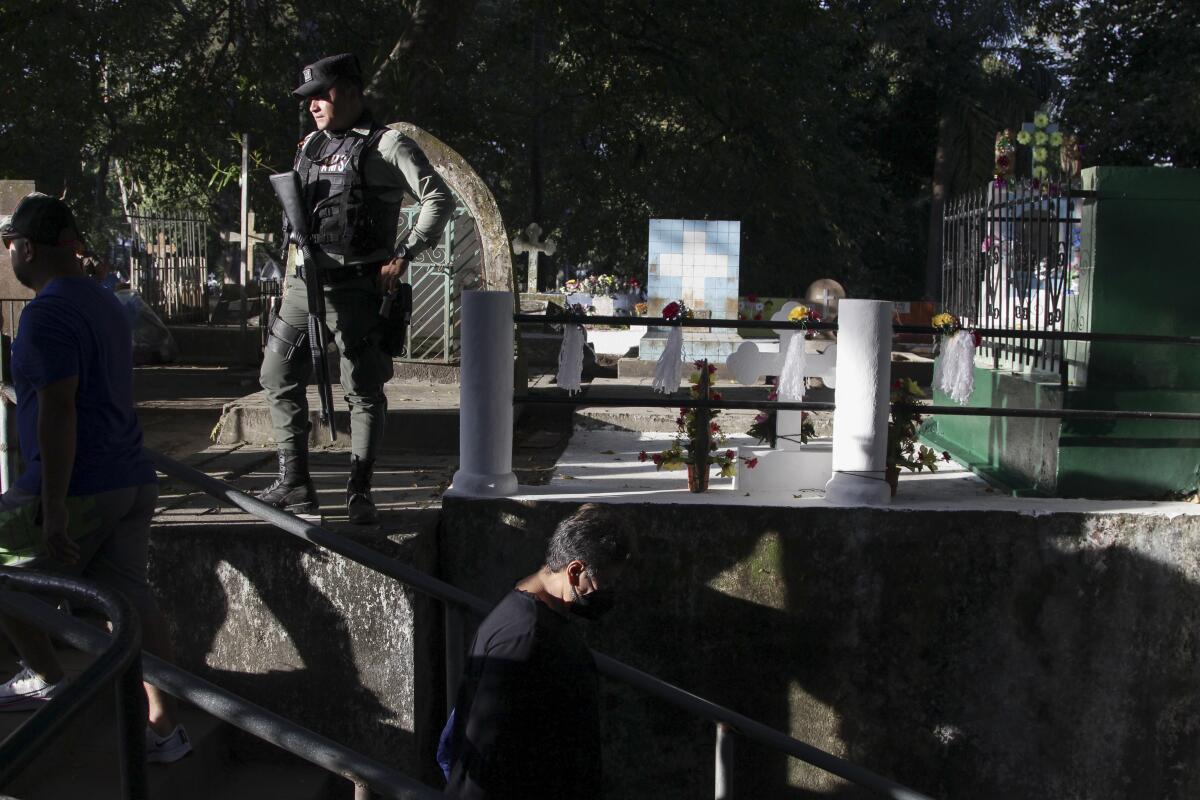 Un oficial de policía permanece de guardia en una de las áreas del Cementerio Nueva San Salvador, 