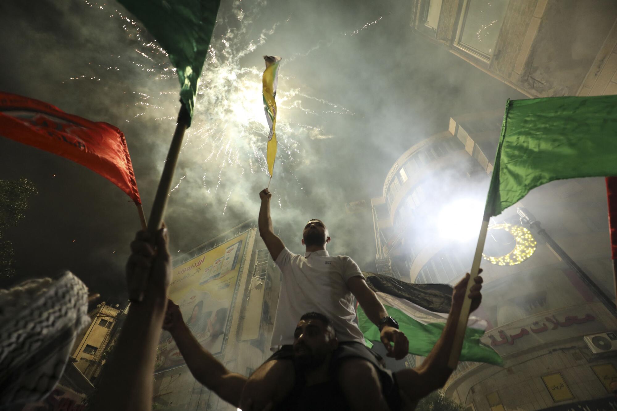 People wave flags as fireworks go off overhead