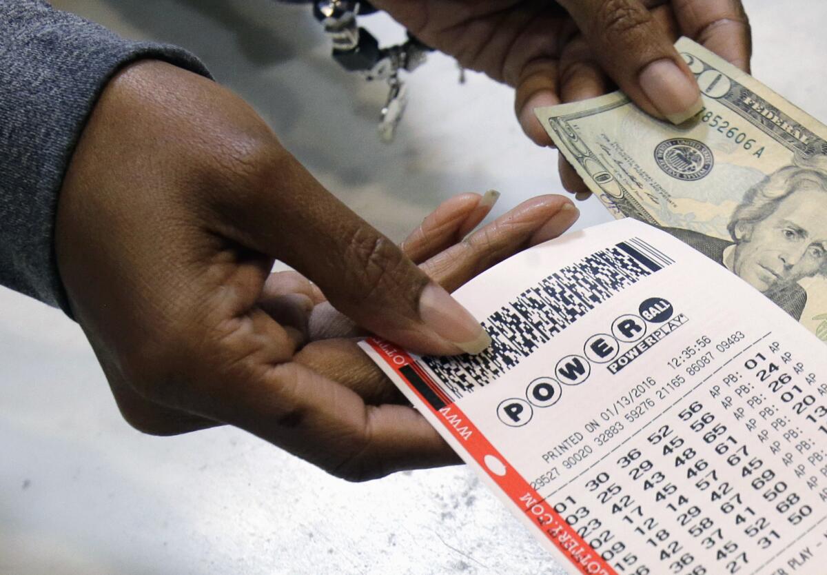 A clerk hands over a Powerball ticket for cash at Tower City Lottery Stop in Cleveland.