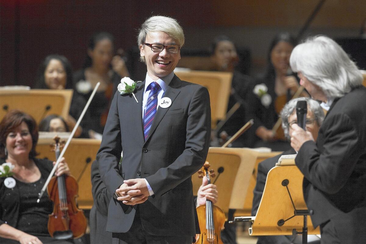 Thai composer Narong Prangcharoen smiles while introduced onstage by Pacific Symphony conductor Carl St.Clair, far right, during opening night at the Renee and Henry Segerstrom Concert Hall in Costa Mesa on Thursday. Prangcharoen composed a piece about Orange County called "Beyond Land and Ocean".