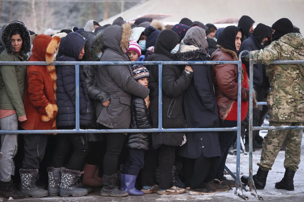 Migrants queue to get hot food in the logistics center of the checkpoint "Bruzgi" at the Belarus-Poland border near Grodno, Belarus, Wednesday, Dec. 1, 2021. The West has accused Belarusian President Alexander Lukashenko of luring thousands of migrants to Belarus with the promise of help to get to Western Europe to use them as pawns to destabilize the 27-nation European Union in retaliation for its sanctions on his authoritarian government. Belarus denies engineering the crisis. (Oksana Manchuk/BelTA via AP)