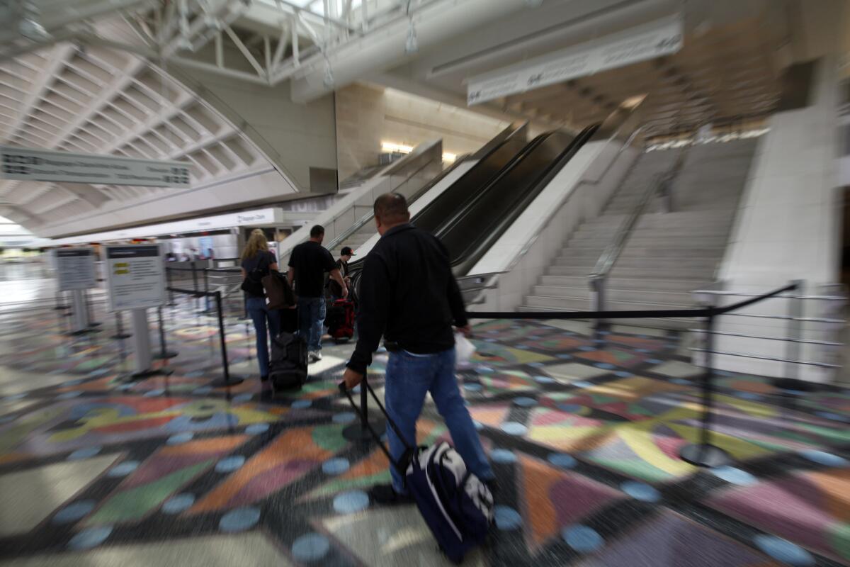 Travelers walk toward the security check-in at Ontario International Airport.