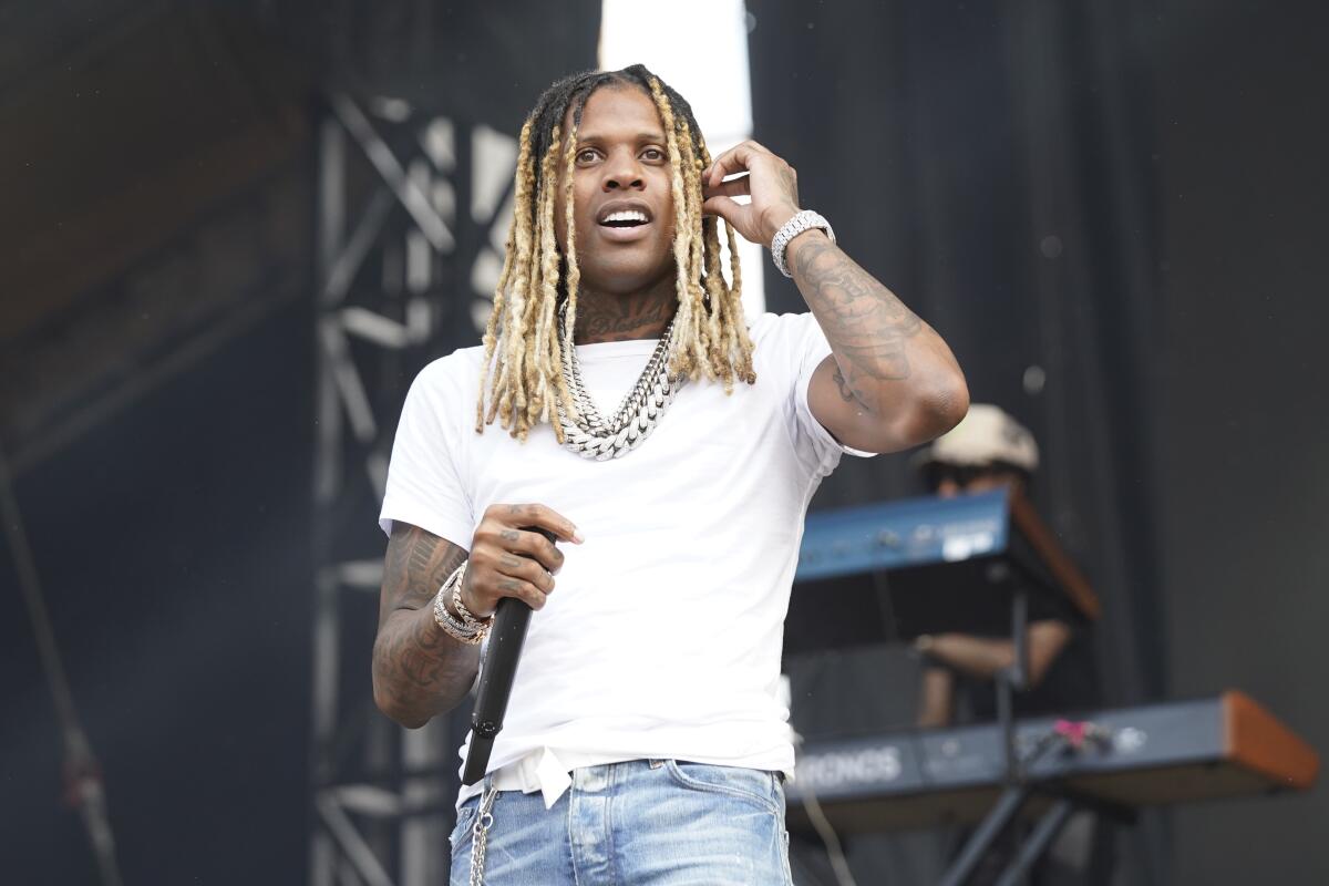 Lil Durk wears a plain, white shirt and blue jeans as he performs onstage