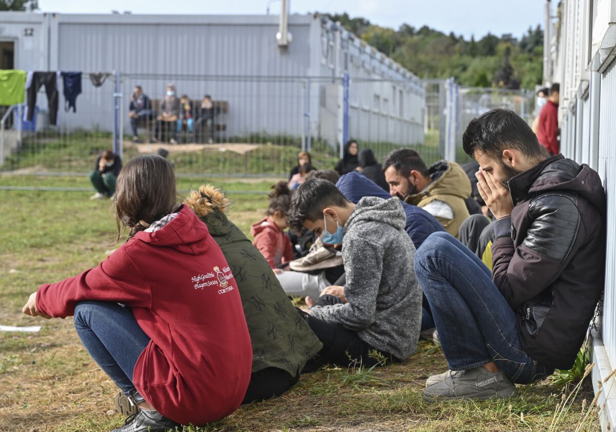 Migrants sit in front of containers at the Central Initial Reception Facility for Asylum Seekers, ZABH, in the federal German state of Brandenburg in Eisenhuettenstadt, Germany, Wednesday, Oct. 6, 2021. German federal police said more than 4,300 people crossed the border from Poland 'illegally' this year. Most people are being put up at asylum centers in the eastern state of Brandenburg. (Patrick Pleul/dpa via AP)