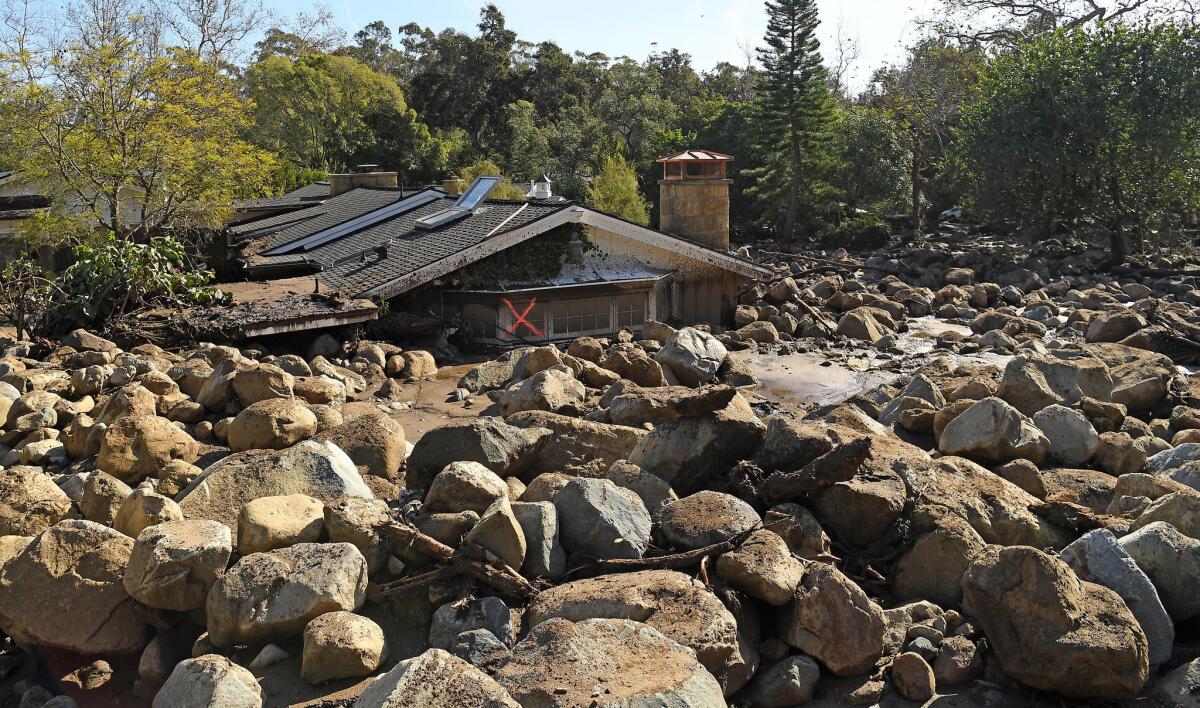 A house is left among boulders and mud along Glen Oaks Drive in Montecito.