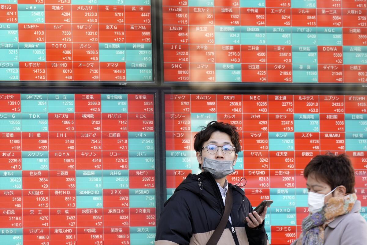 People stand in front of an electronic stock board in Tokyo.
