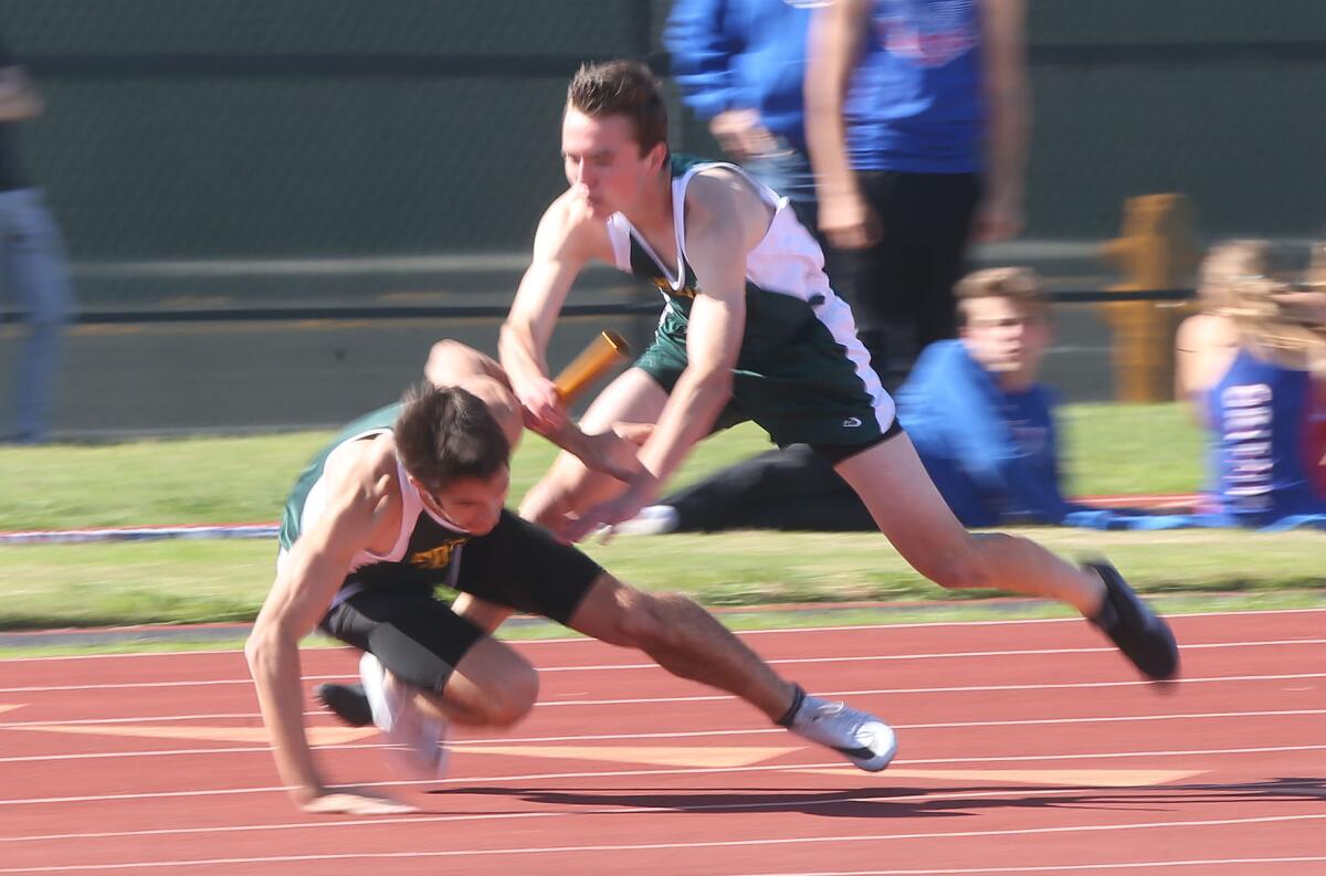 Edison's Conor Zeutzius, right, and teammate Jack de Bos get tangled up on the baton exchange on the last leg of the 400-meter relay during the Surf League dual meet against Los Alamitos on Wednesday.