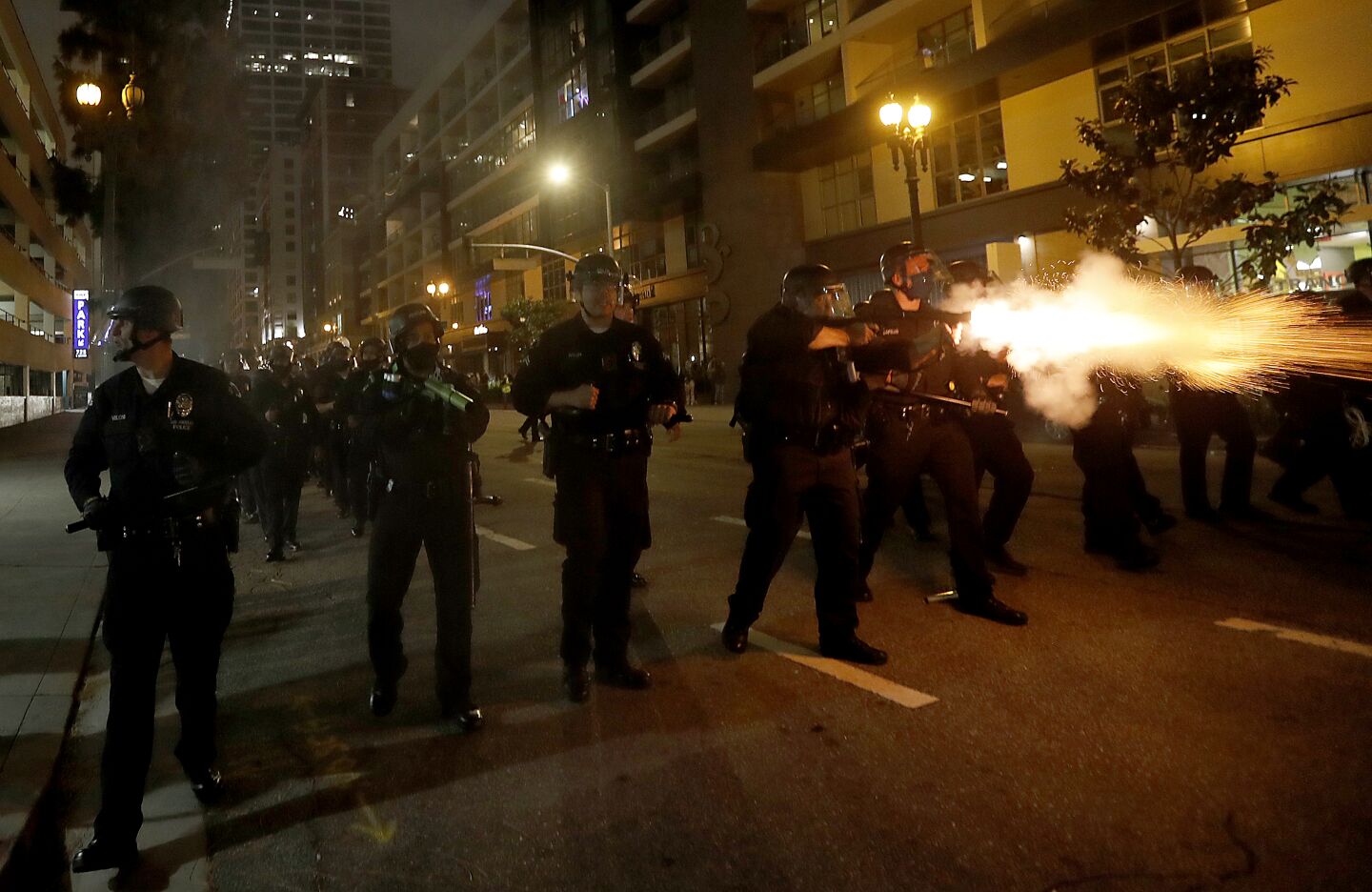 Police fire percussion rounds to clear protesters from Grand Avenue in in downtown Los Angeles on Friday.