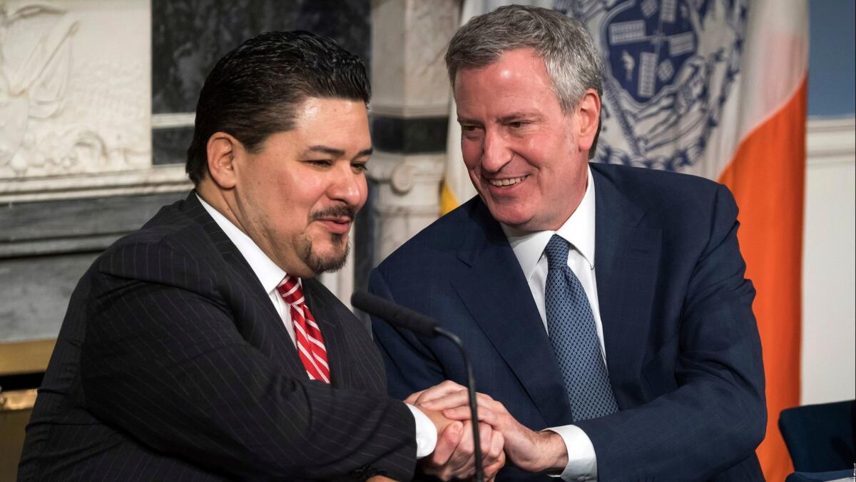 New York Mayor Bill de Blasio, right, holds tight to this one as he welcomes Richard A. Carranza on Monday to the city as the new chancellor of schools. The mayor's first choice, Alberto Carvahlo, had changed his mind.