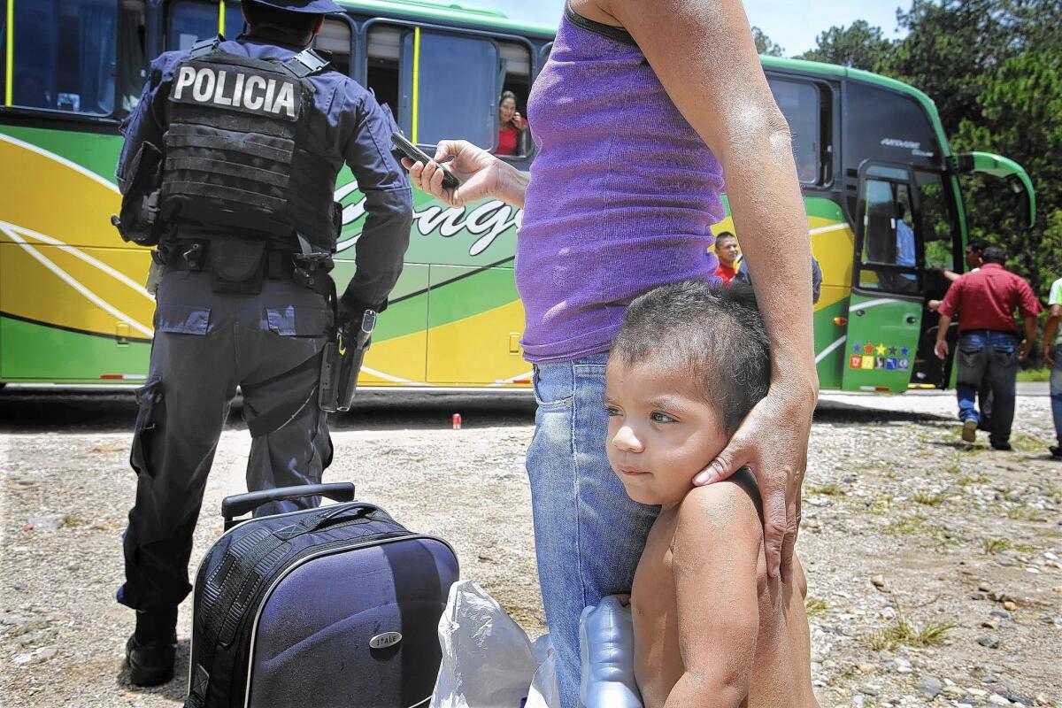 As other passengers reboard a Guatemala-bound bus that was stopped at a police checkpoint near Ocotepeque, Honduras, in July, 2-year-old Yahir clings to his mother, Ana Maria Ramos.