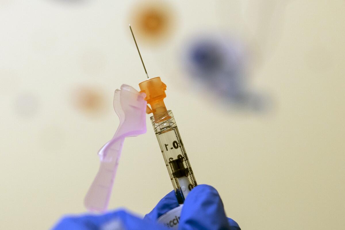A nurse prepares a vaccine dose