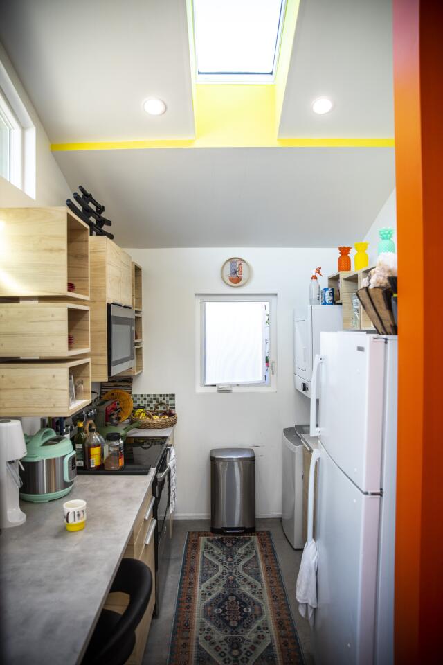 A narrow kitchen has modular storage on the walls and a counter with seating.