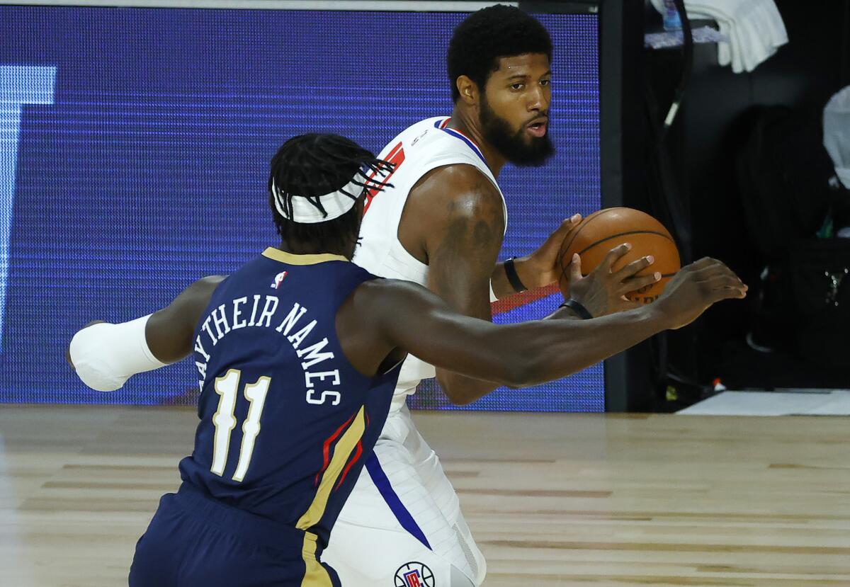 Clippers' Paul George drives past New Orleans Pelicans' Jrue Holiday during the first half.