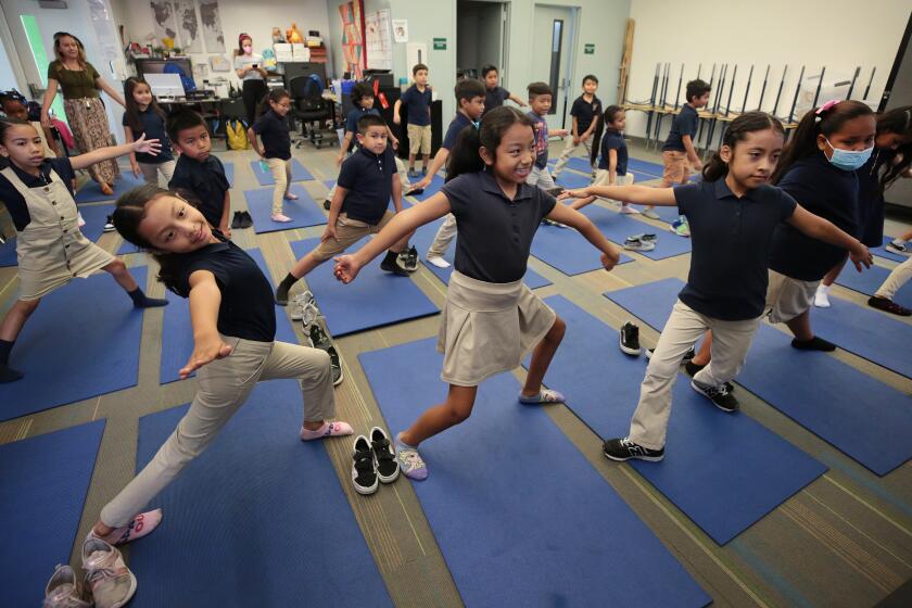 Los Angeles, CA - September 14: Accelerated Charter Elementary School on Wednesday, Sept. 14, 2022 in Los Angeles, CA. 2nd grade students Sophia Galarza, Jasmine Saloj and Giselle Calderon stretch to instructions from Yoga instructor Sacha Taylor and Leah Gallegos, a co-founder of People's Yoga as they lead students at Accelerated Charter Elementary School in Los Angeles in a half hour yoga session. People's Yoga, which may be the only yoga studio in East L.A. was created to offer accessible yoga classes in that geography. (Al Seib / For The Times)