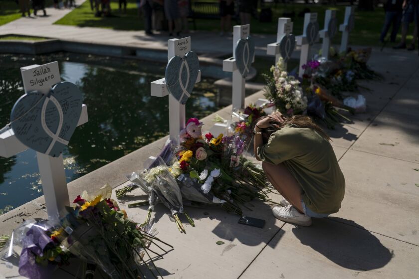 Elena Mendoza, 18, grieves in front of a cross honoring her cousin, Amerie Jo Garza, one of the victims killed in this week's elementary school shooting in Uvalde, Texas, Thursday, May 26, 2022. (AP Photo/Jae C. Hong)