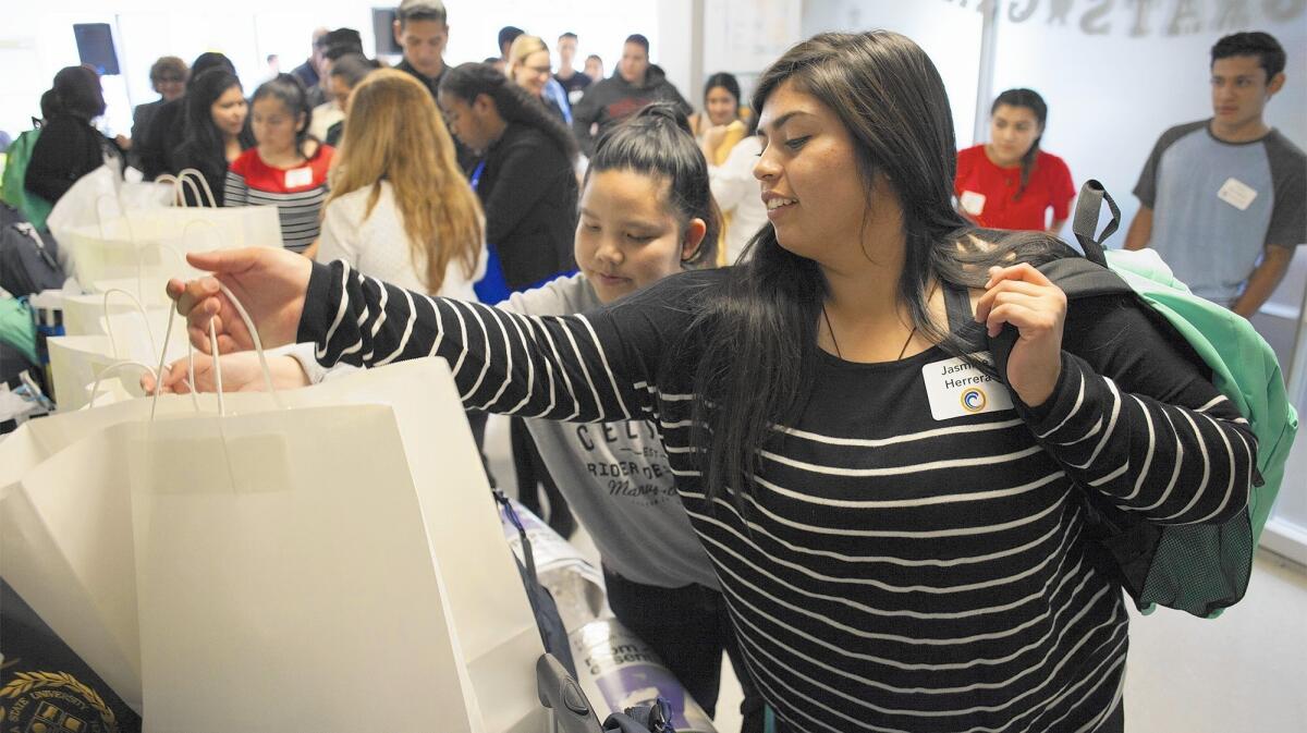 Costa Mesa High School seniors Jasmine Herrera, right, and Carol Hoang search out goody bags with their names on them during a Share Our Selves high school senior project ceremony. Herrera and Hoang will attend Orange Coast College.