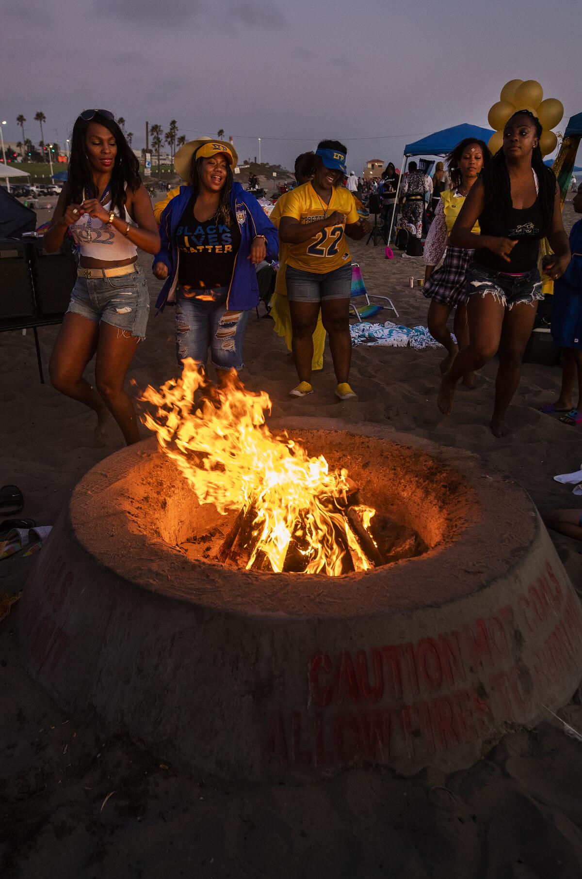 Members of the Sigma Gamma Rho sorority dance next to their bonfire at Dockweiler State Beach.