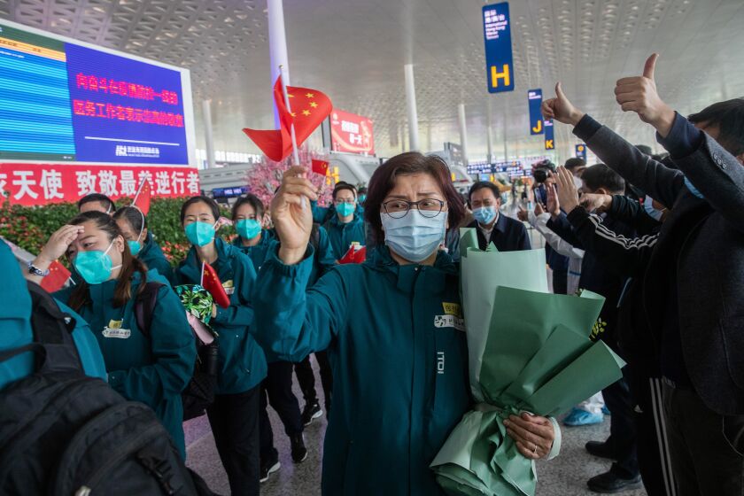 Medical staff members (in green) from Peking Union Medical College Hospital wave national flags before leaving at Tianhe airport in Wuhan in China's central Hubei province on April 15, 2020. - Medical staff from Peking Union Medical College Hospital is the last medical assistance team from other provinces leaving Wuhan after helping with the COVID-19 coronavirus recovery effort. (Photo by STR / AFP) / China OUT (Photo by STR/AFP via Getty Images)