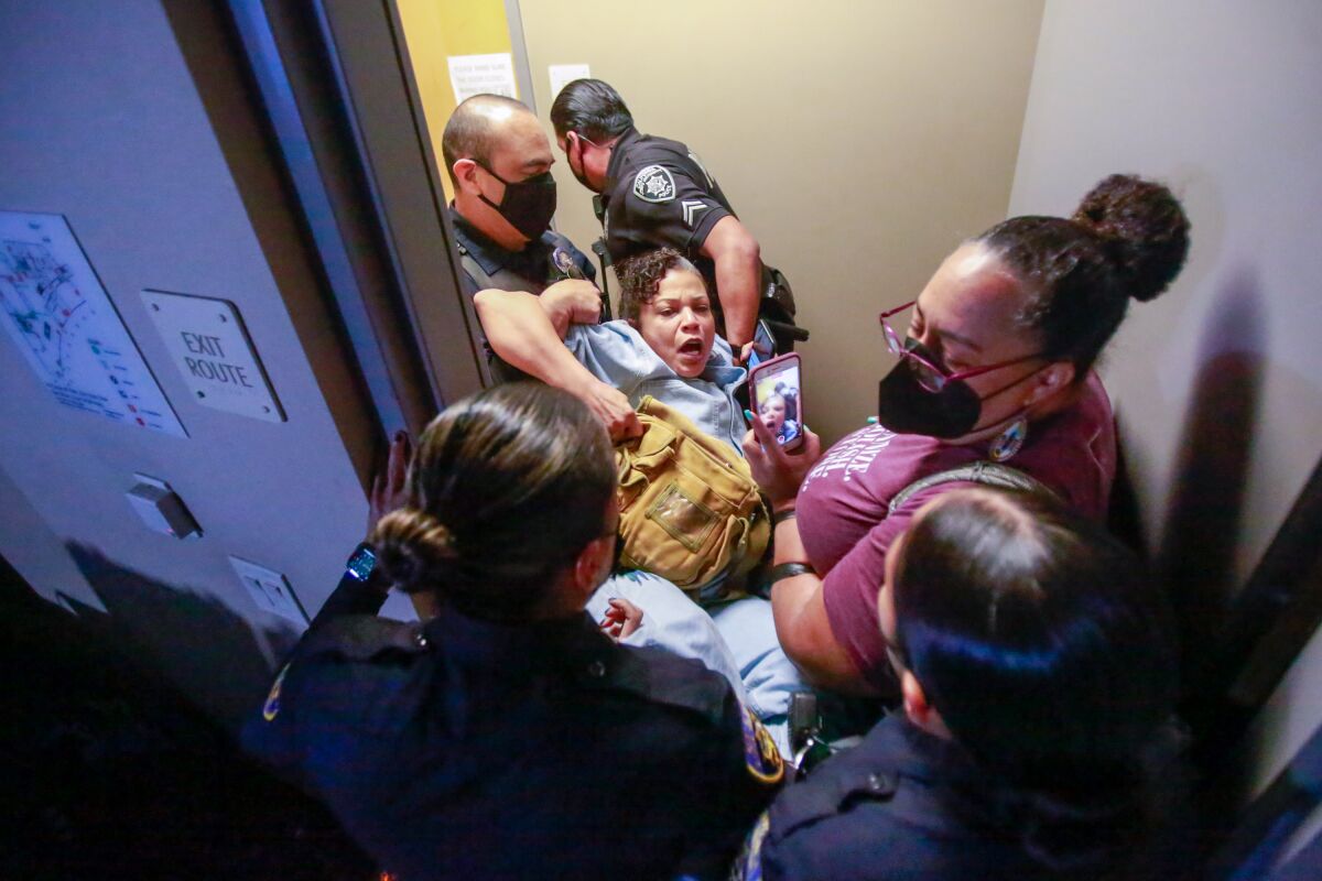 Police carry a woman through a doorway