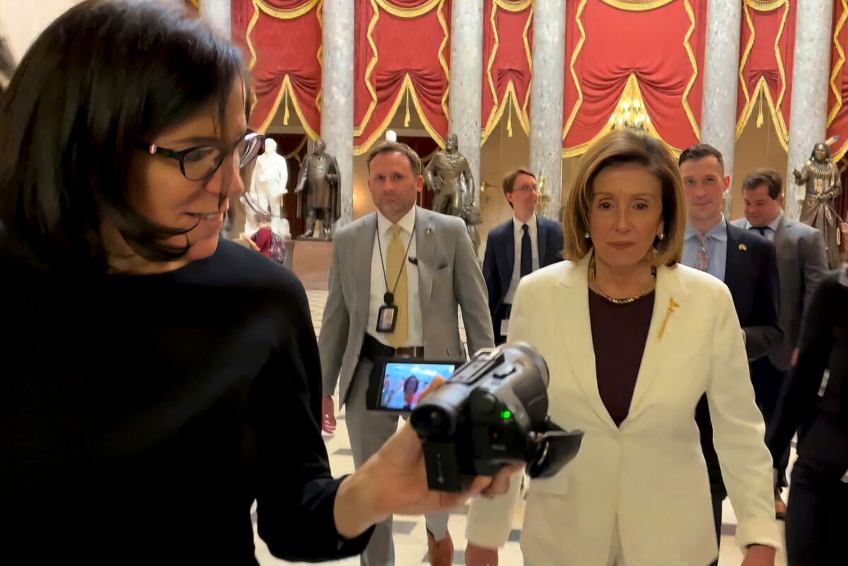 A woman aims a camera at a woman in a white jacket.