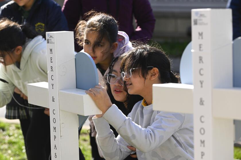 Children sign a cross at an entry to Covenant School, Tuesday, March 28, 2023, in Nashville, Tenn., which has become a memorial to the victims of Monday's deadly school shooting. (AP Photo/John Amis)