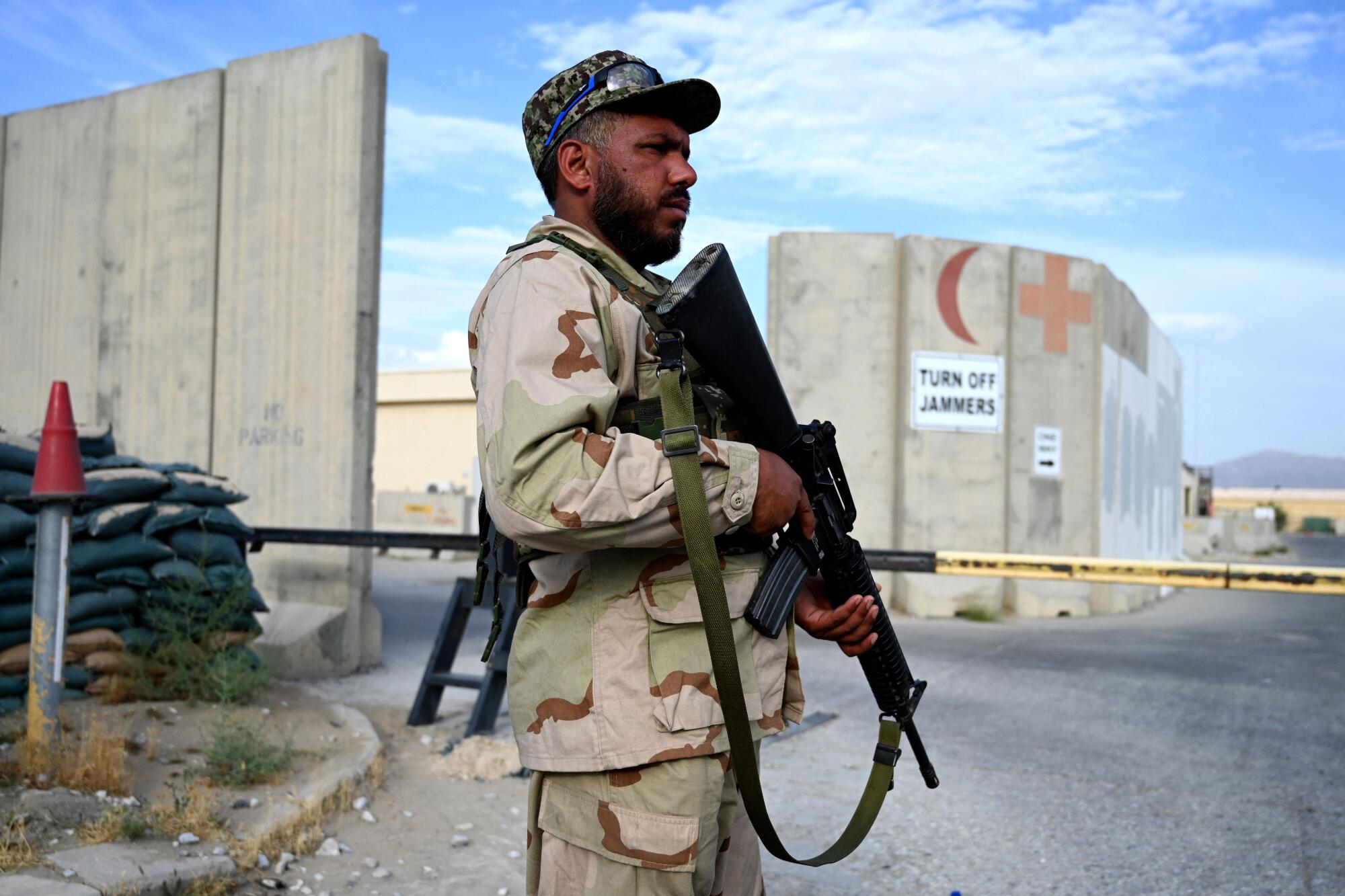 Armed Afghan soldier stands guard at a gate  