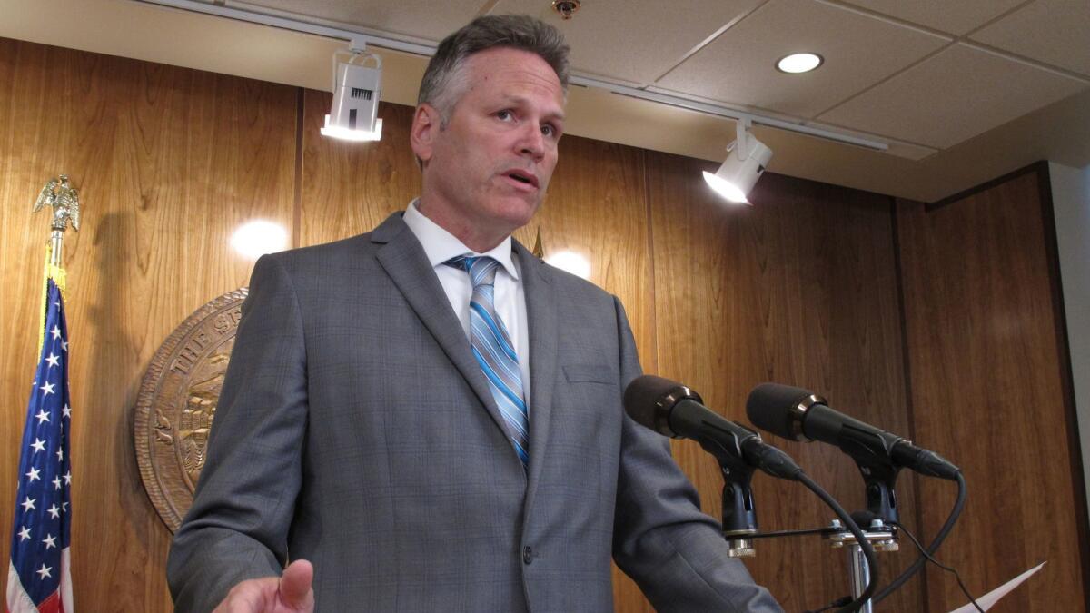 Alaska Gov. Mike Dunleavy speaks to reporters about his budget vetoes at the state Capitol in Juneau on June 28.