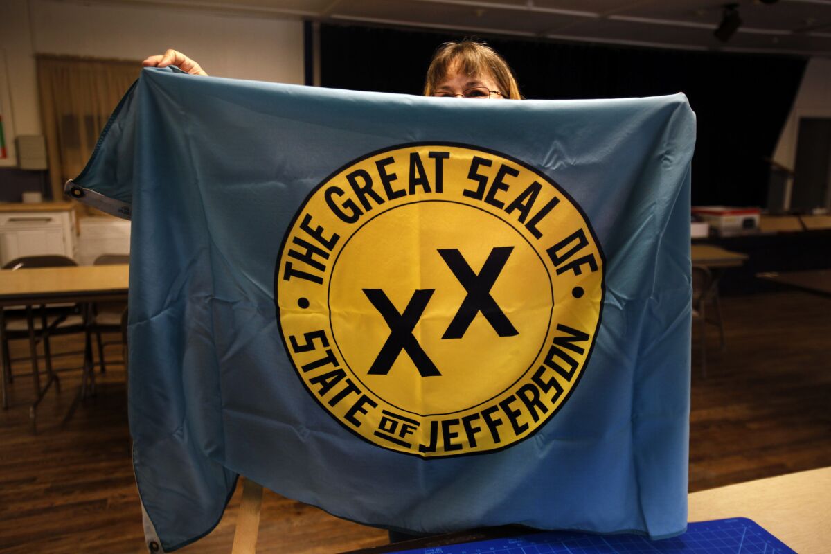 A woman holds a banner with the seal of a secession effort in 1941 that involved rural counties in Oregon and California.