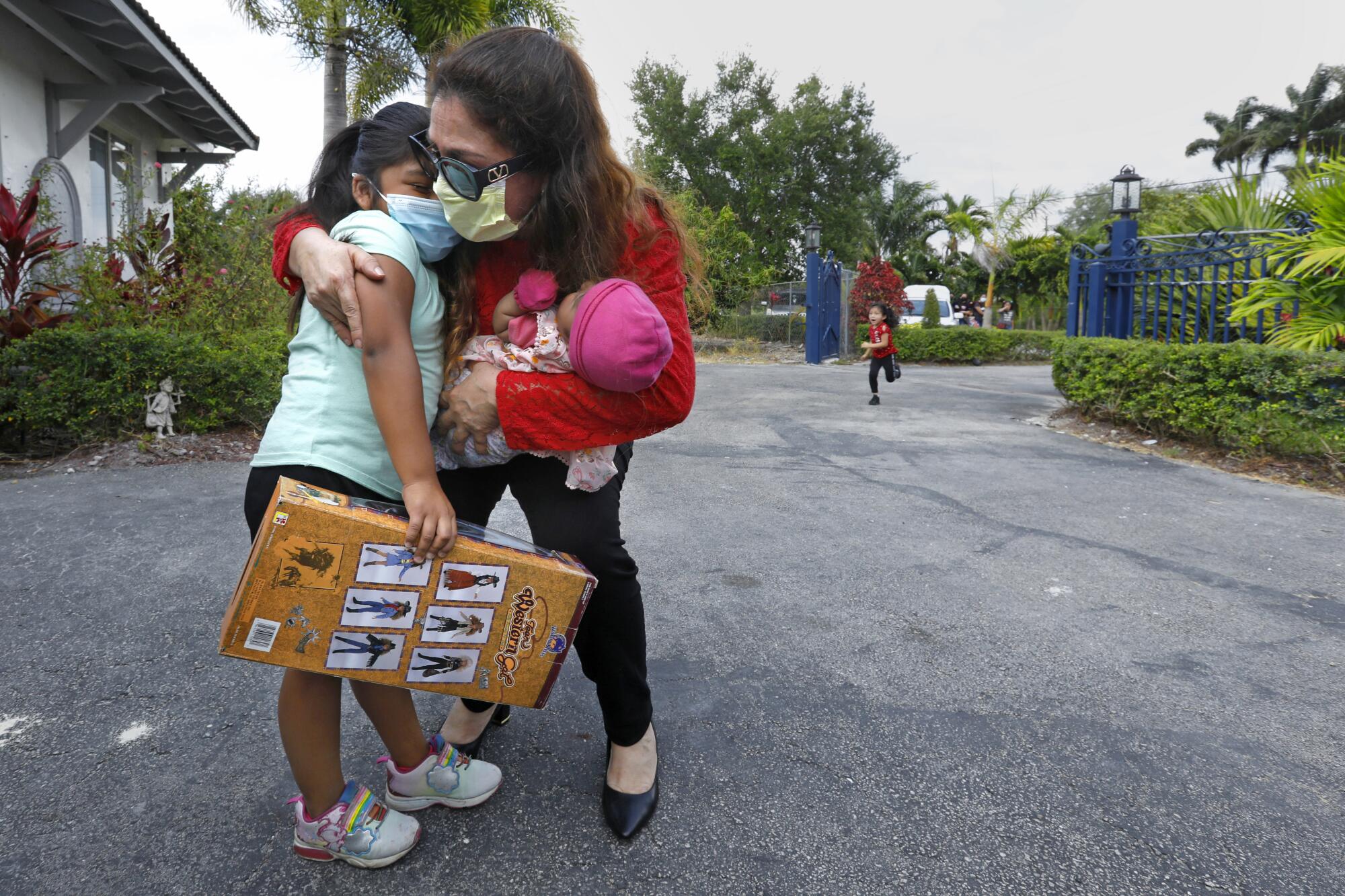 Nora Sandigo hugs a child and holds an infant.