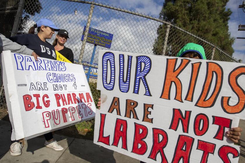 ENCINO, CA - October 18 2021: Parents and students from around the San Fernando Valley hold signs and shout as a protest against vaccine mandates in front of Birmingham High School on Monday, Oct. 18, 2021 in Encino, CA. (Brian van der Brug / Los Angeles Times)
