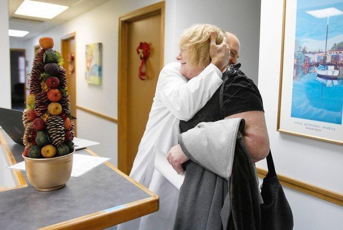 Dr. Damian Folch hugs Martha Thomas, 54, after her appointment at his office in Chelmsford, Mass. Folch is among thousands of physicians in Massachusetts whose pay depends on how their patients fare.