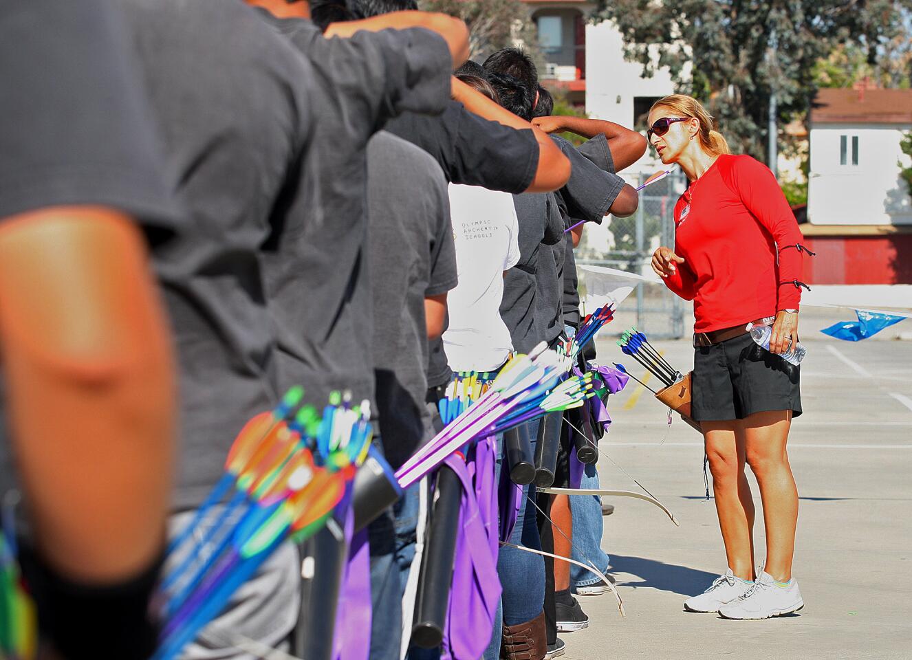 U.S. Olympic archer Khatuna Lorig looks closely at the form of a Glendale High School archer during a visit to the school on Tuesday, April 29, 2014. Lorig came to the archery program for the day at Glendale High School to help them develop their technique.